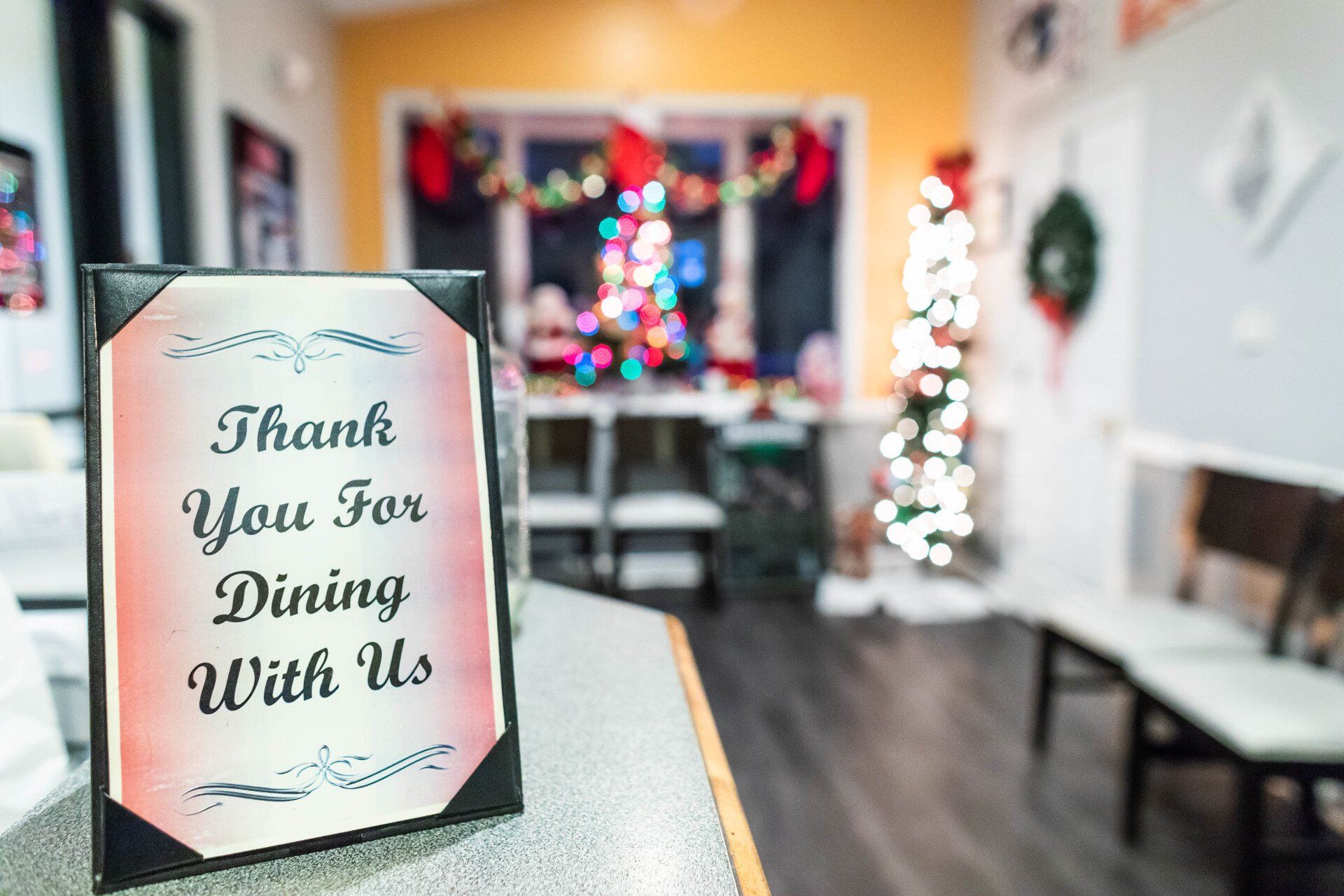 A thank you for dining with us sign is on a counter in a restaurant.