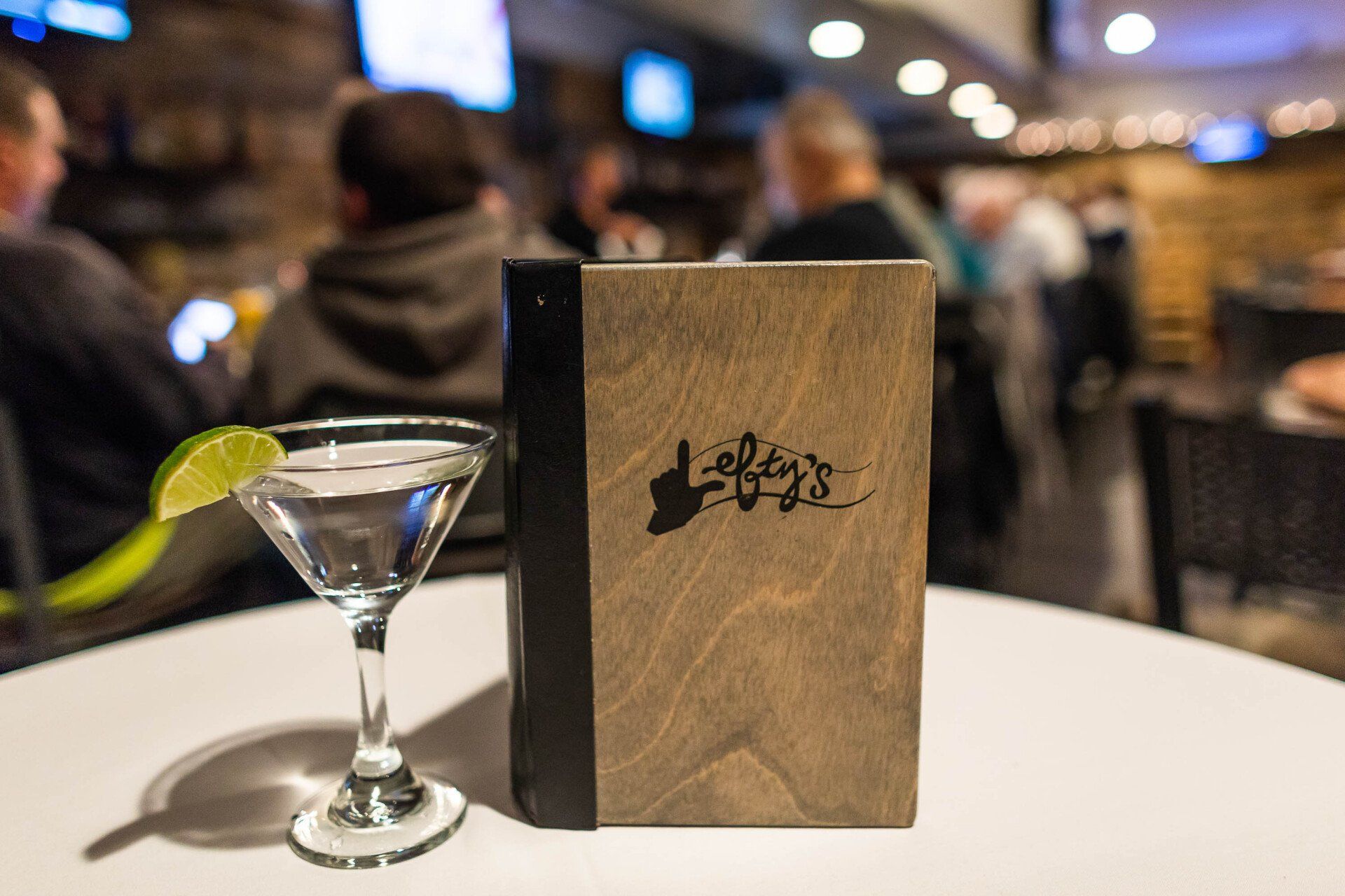 A martini is on a table next to a menu.