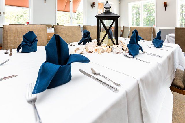 A long table with blue napkins and a lantern on it