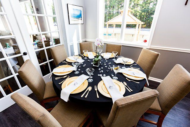 A dining room with a round table and chairs set for a party.