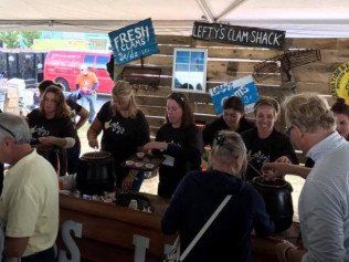 A group of people are standing around a counter at a clam shack.