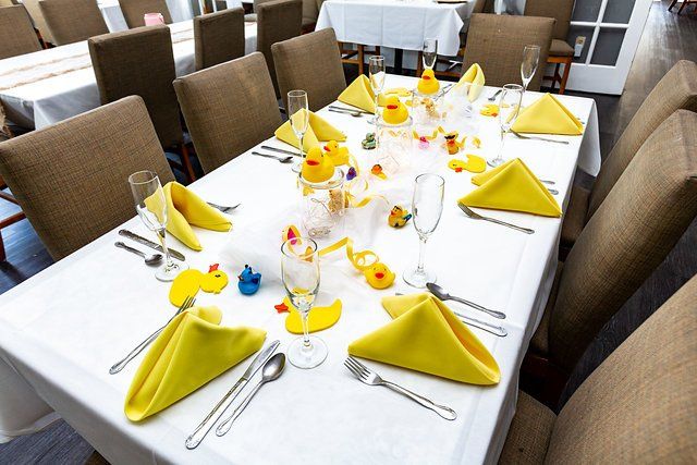 A long table with yellow napkins and rubber ducks on it