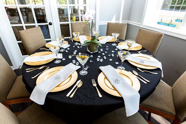 A round table with plates , utensils , and glasses on it.