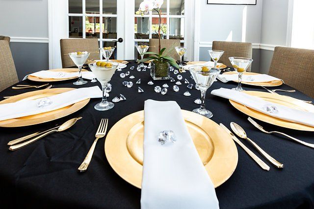 A dining room table is set with plates , utensils , and martini glasses.