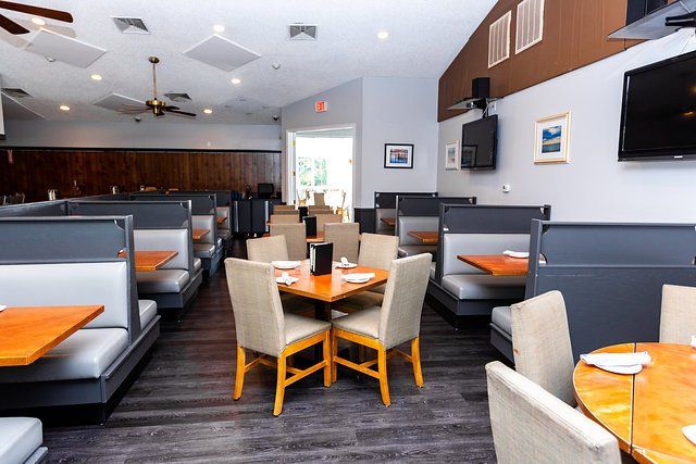 A restaurant with tables and chairs and a television on the wall.
