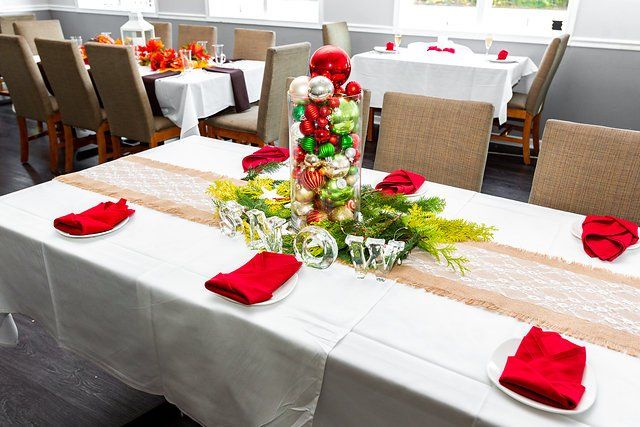 A long table with a vase filled with christmas decorations on it.