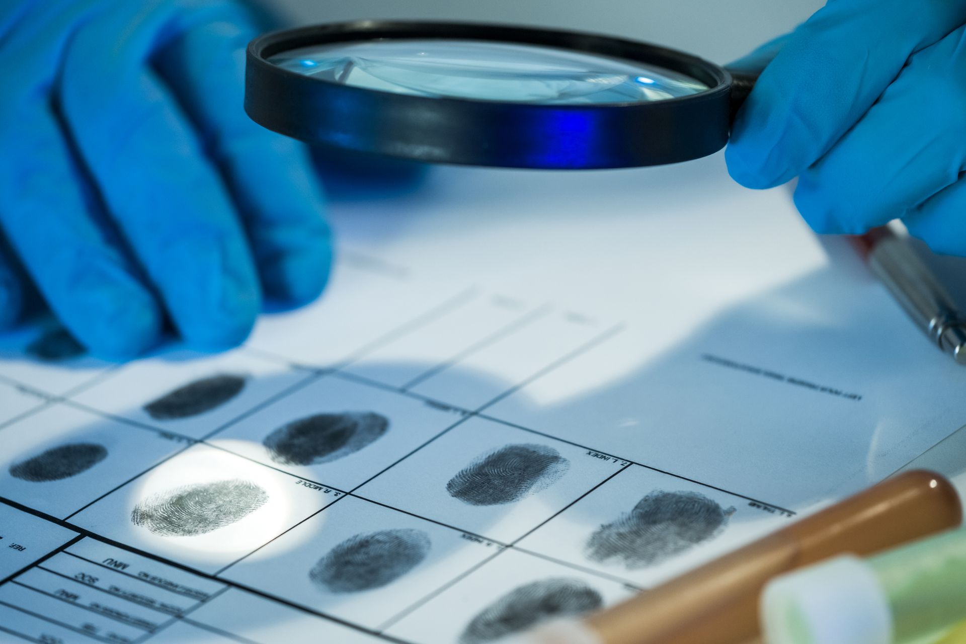 A person is looking at a fingerprint with a magnifying glass.