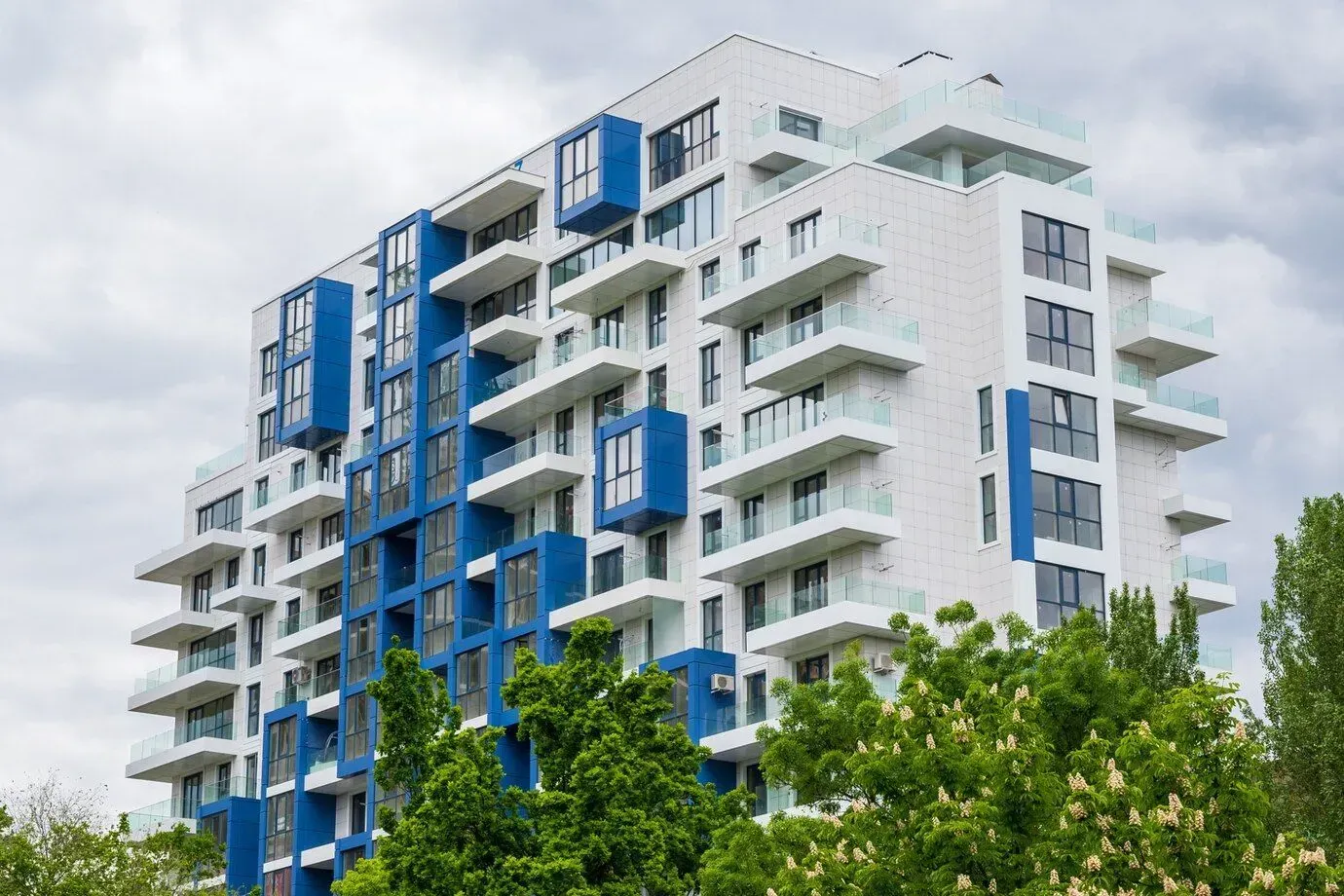 A large blue and white apartment building with trees in front of it in Los Angeles, CA