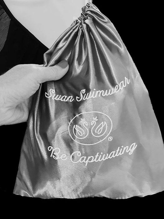 A person is holding a satin bag that says
