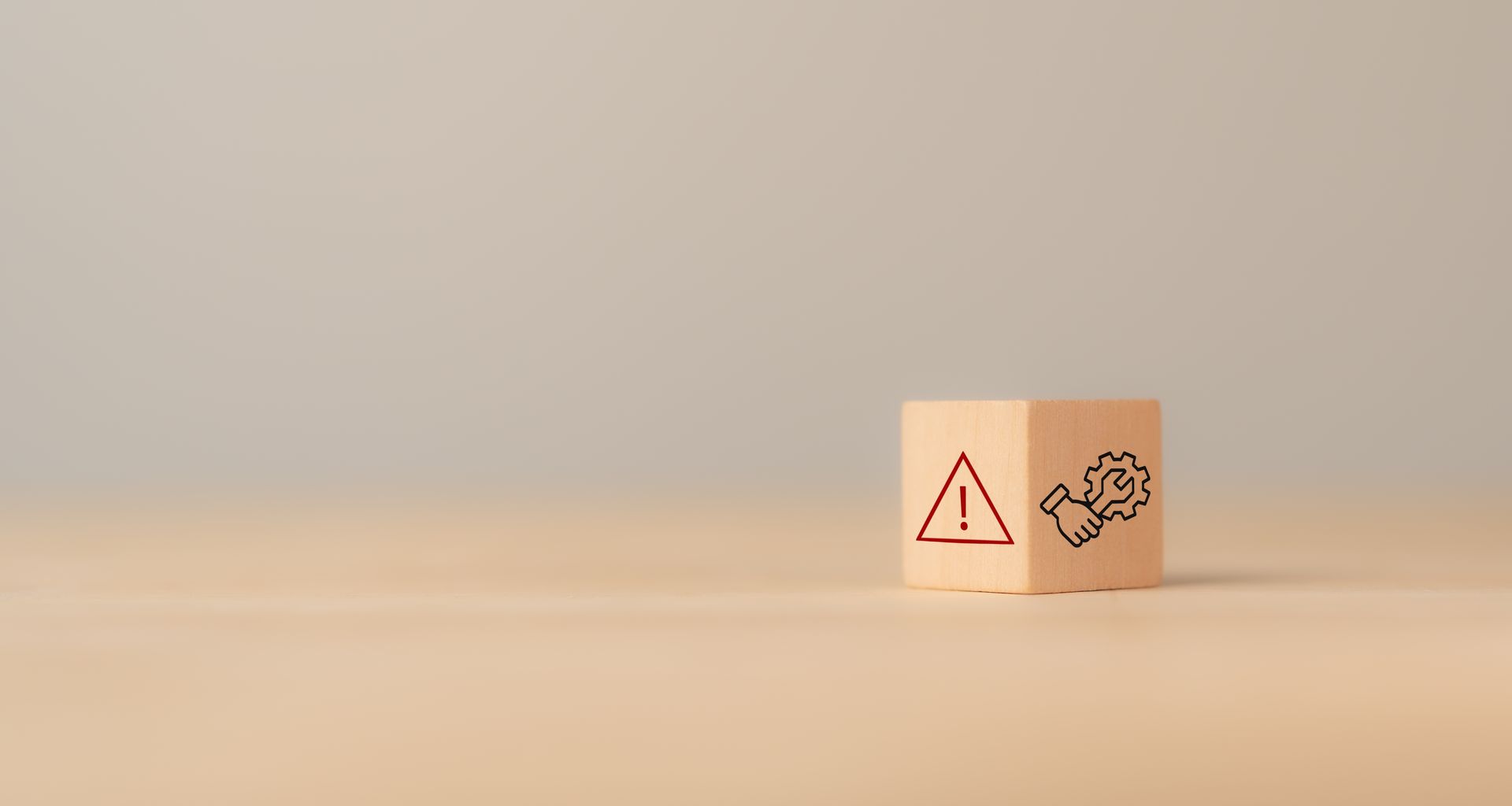 Two wooden blocks on a beige surface, one with a warning triangle and one with a broken heart icon