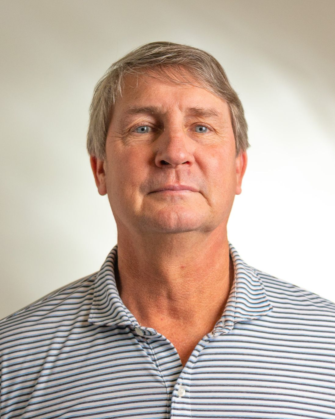Portrait of a man in a striped polo shirt against a plain light background