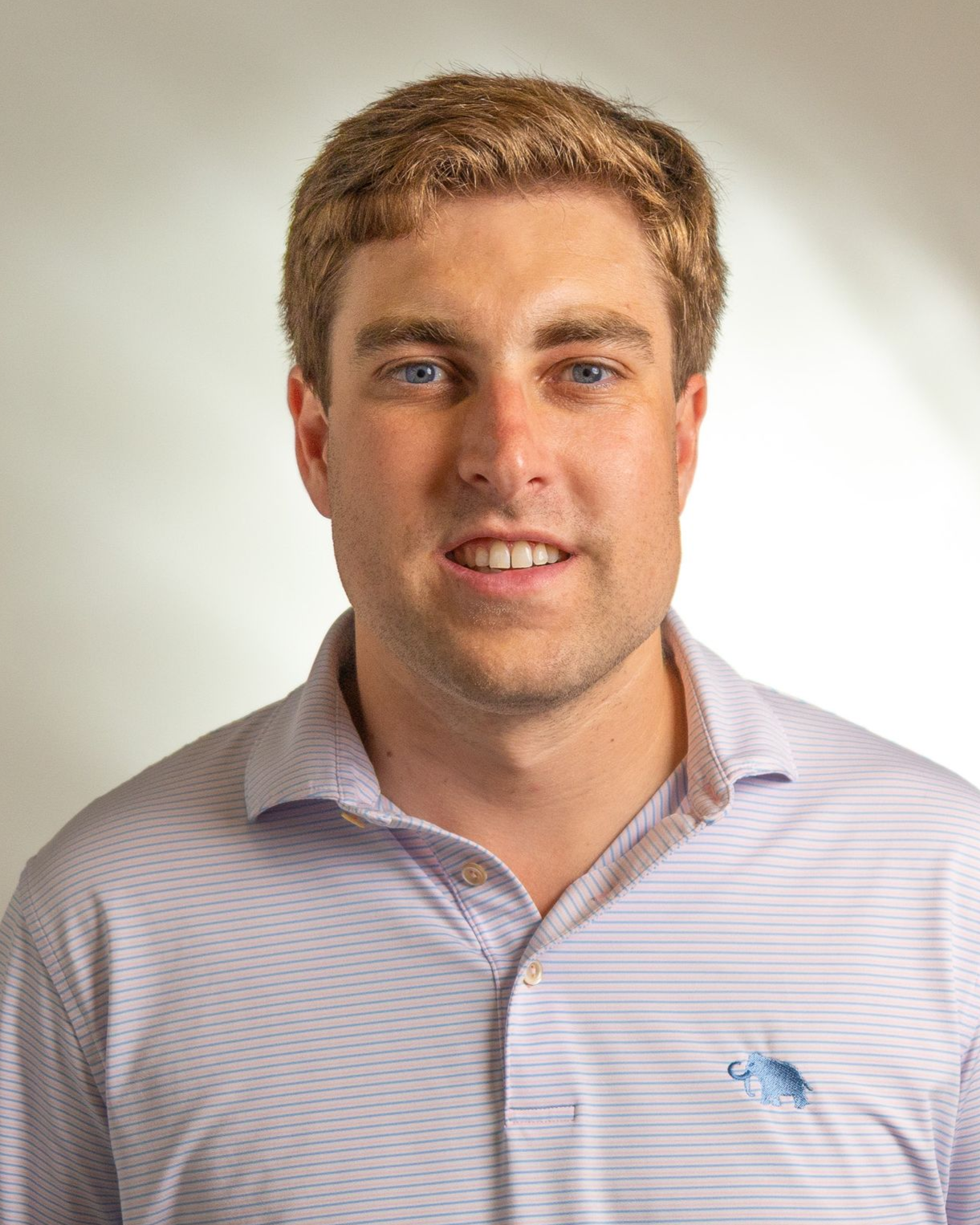 Portrait of a man in a striped button-up shirt against a plain light background