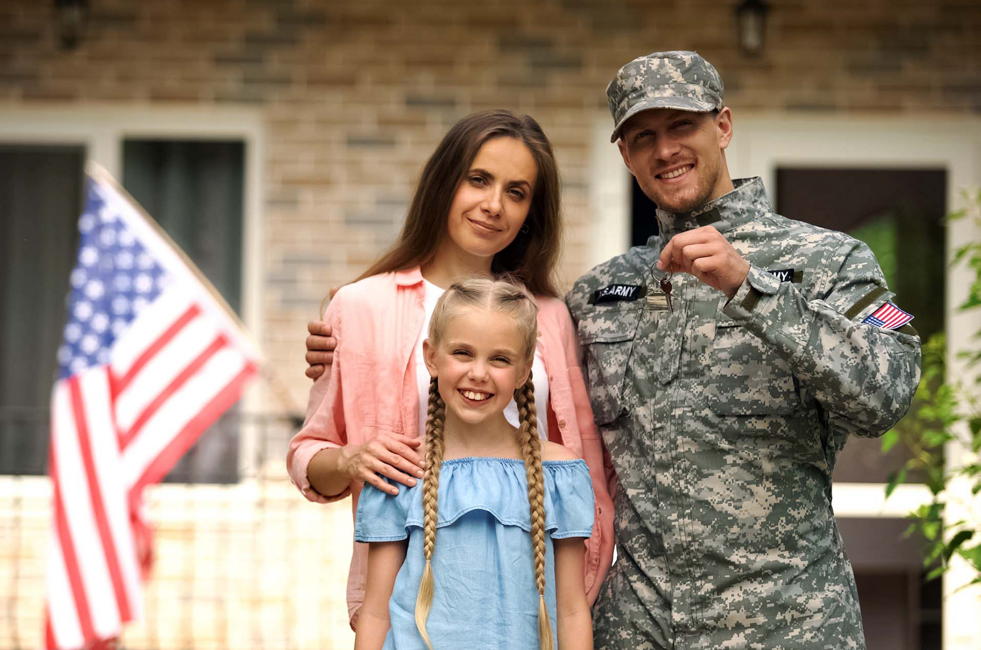 A soldier and his family are standing in front of their new home.