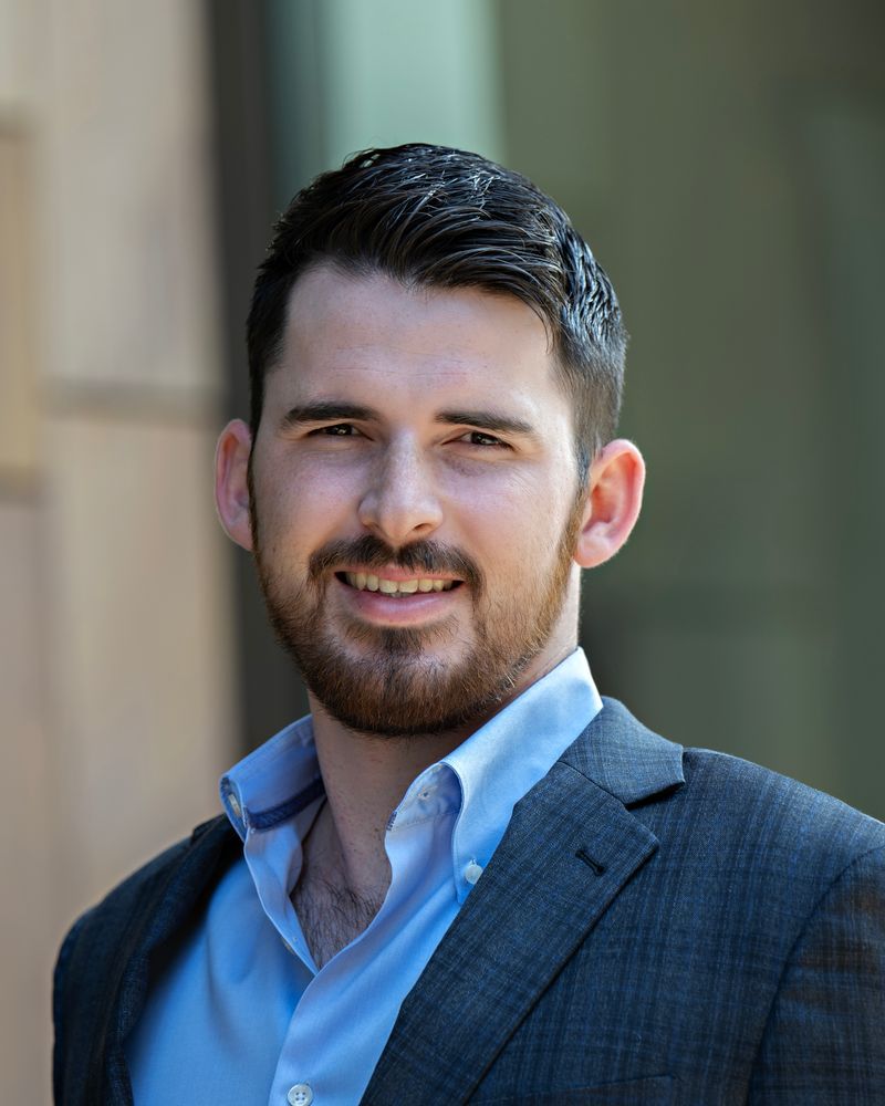 A man with a beard is wearing a suit and smiling for the camera.