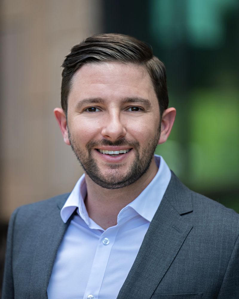 A man in a suit and white shirt is smiling for the camera.