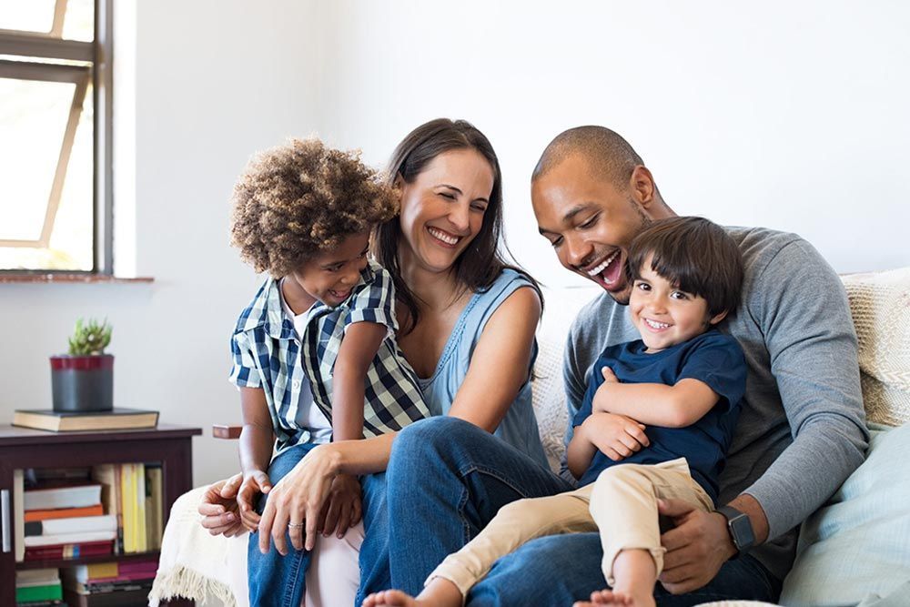 A family is sitting on a couch together and smiling.