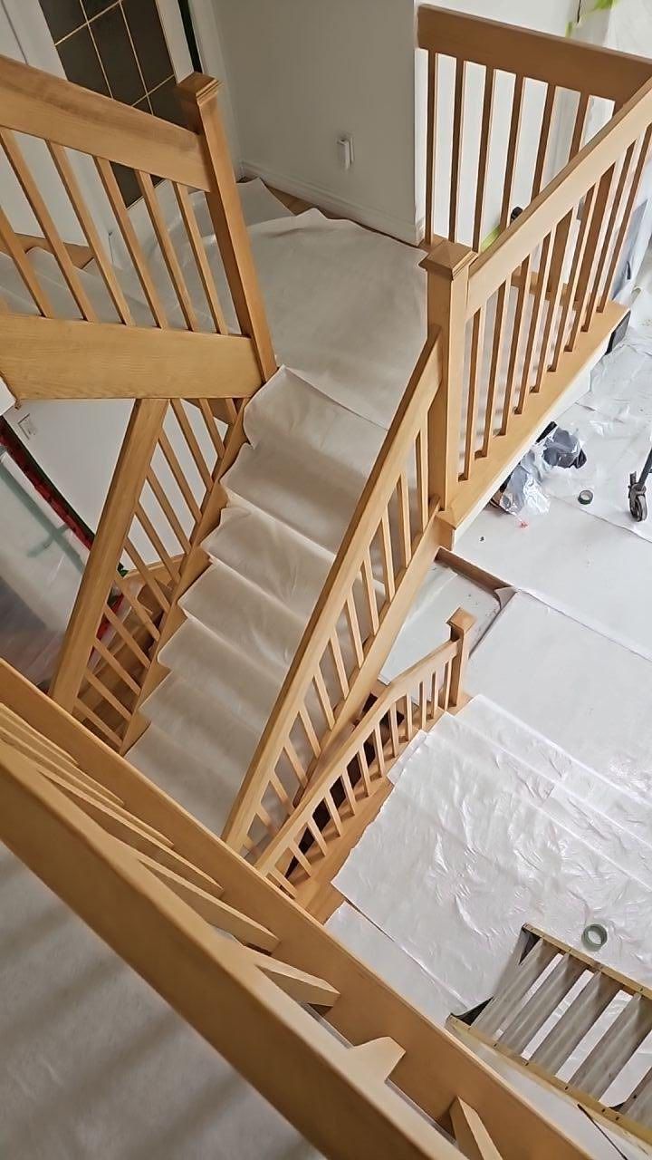 Escalier en bois avec tapis clair et rampes en bois, dans une maison en construction.