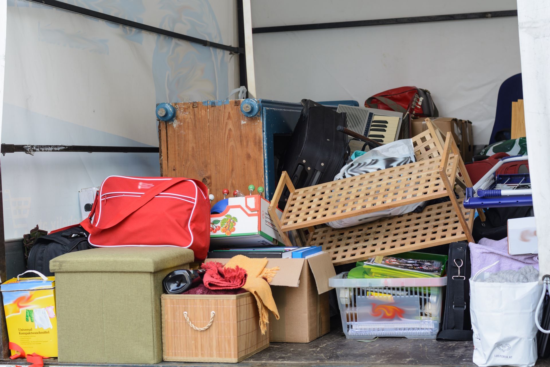 Packed storage items in a truck or trailer, including bags, boxes, and plastic bins.