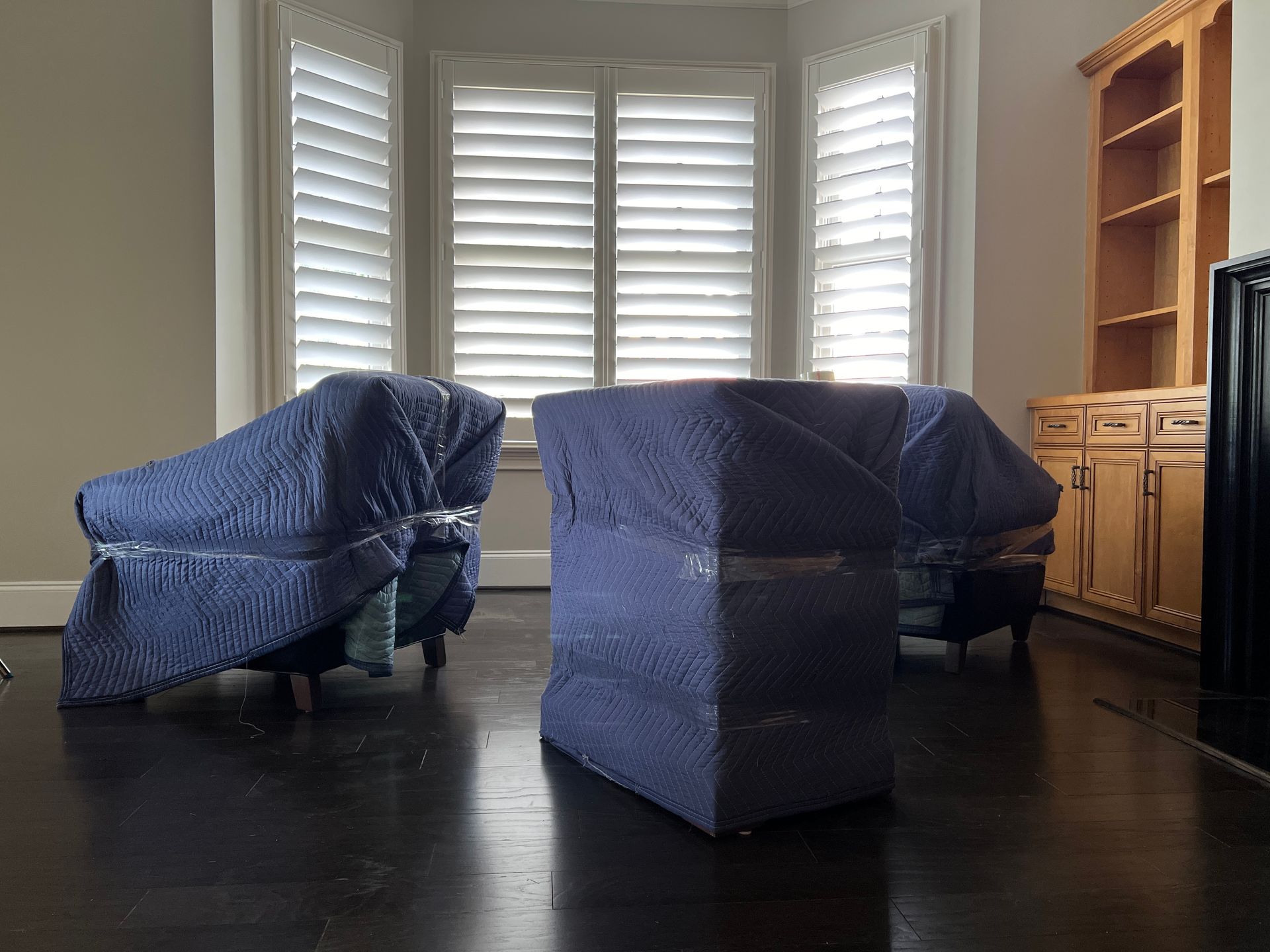 Living room with three blue-covered armchairs and a black table in front of bright windows