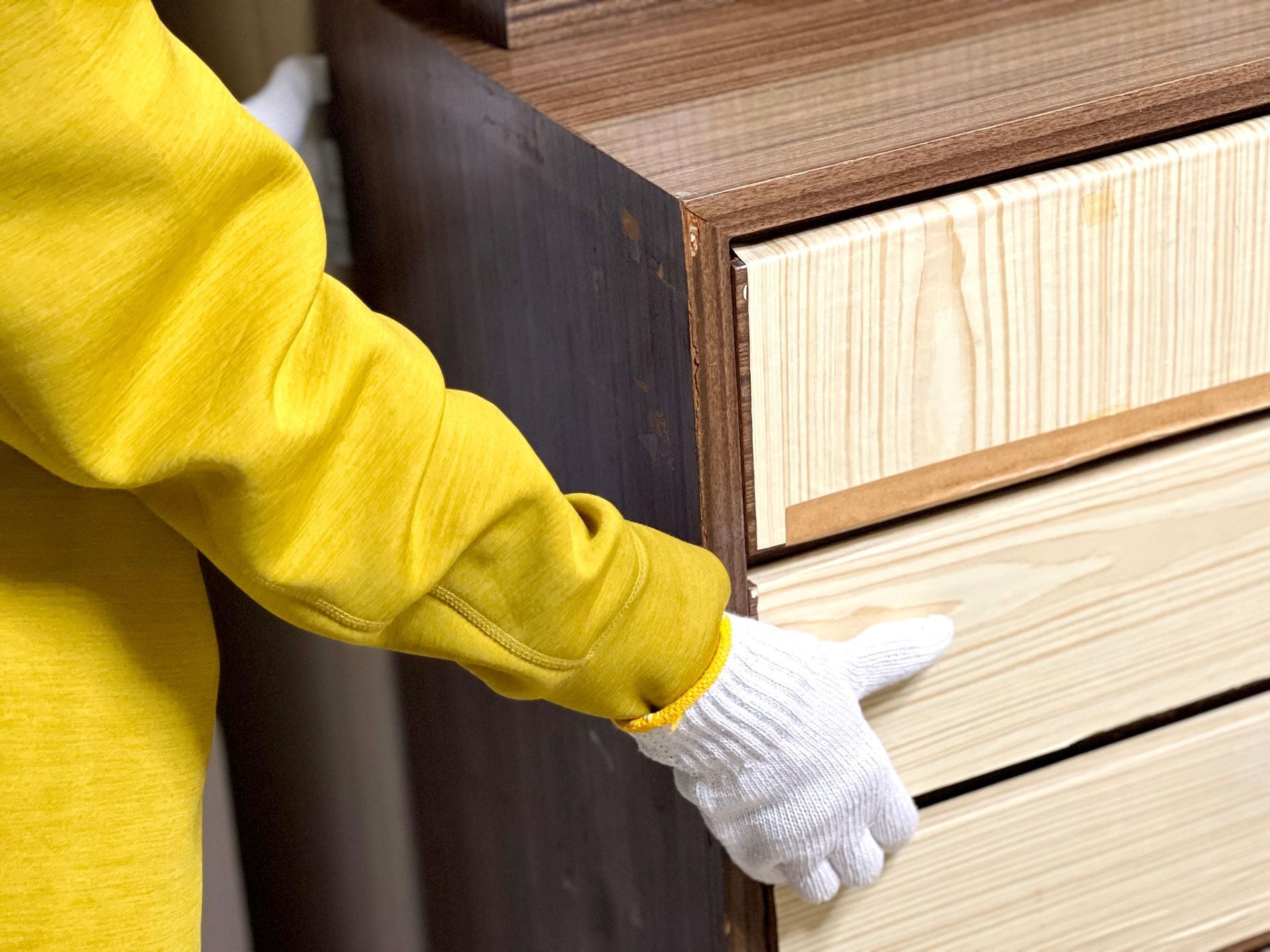 Gloved hand opening a wooden dresser drawer