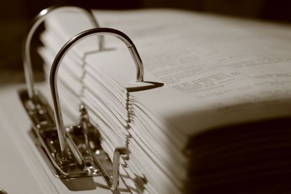 Sepia-toned binder with metal rings holding a thick stack of papers
