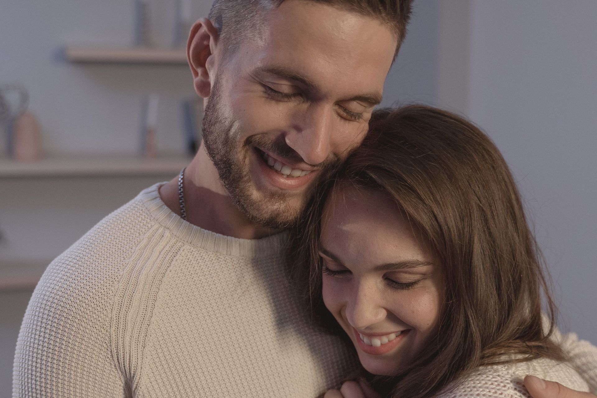 Two people hugging and smiling in a cozy indoor setting