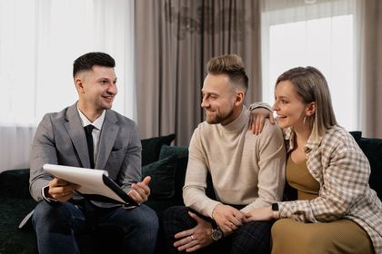 Three people smiling and talking during a counseling session on a couch