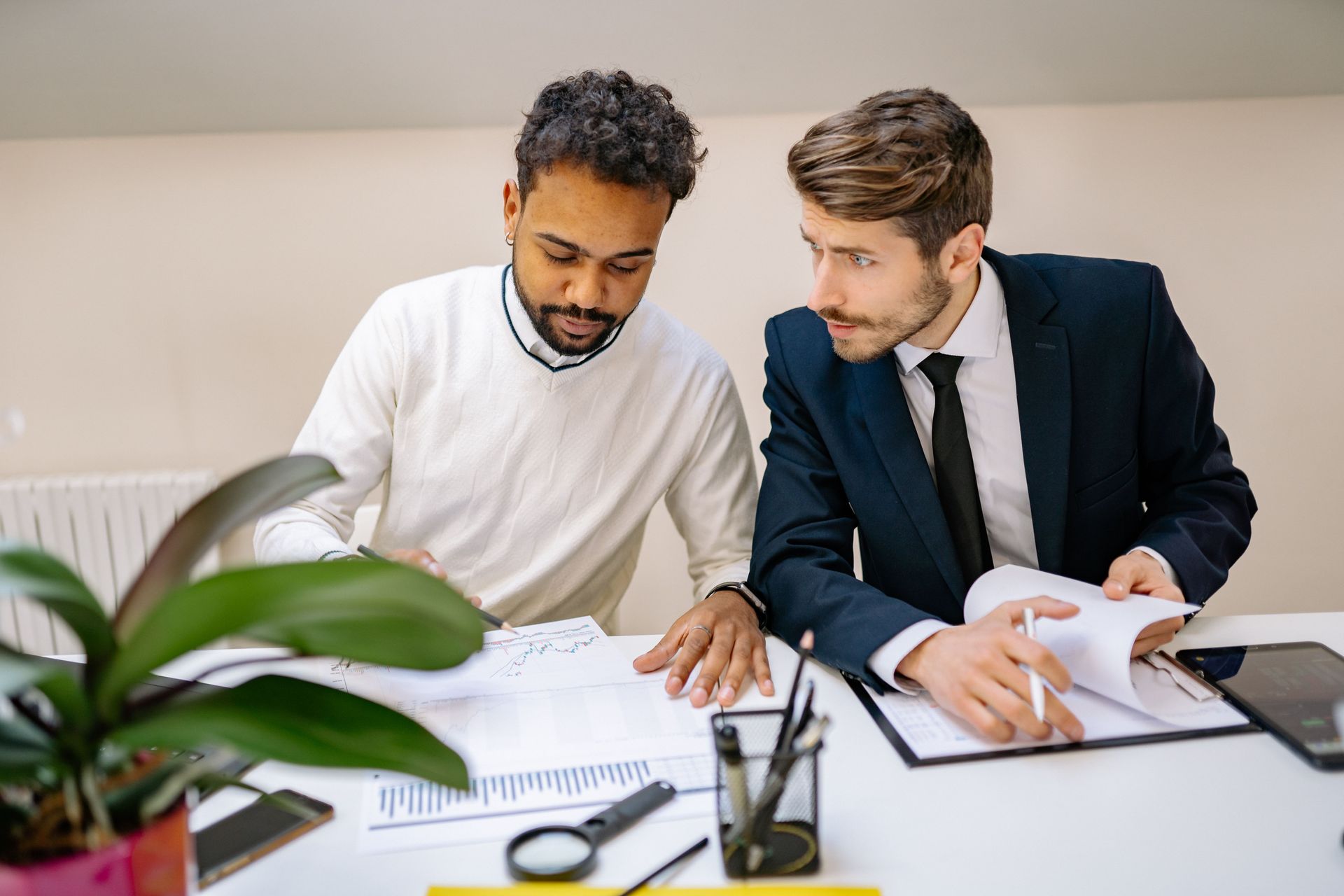 Two coworkers reviewing documents at a desk in a bright office