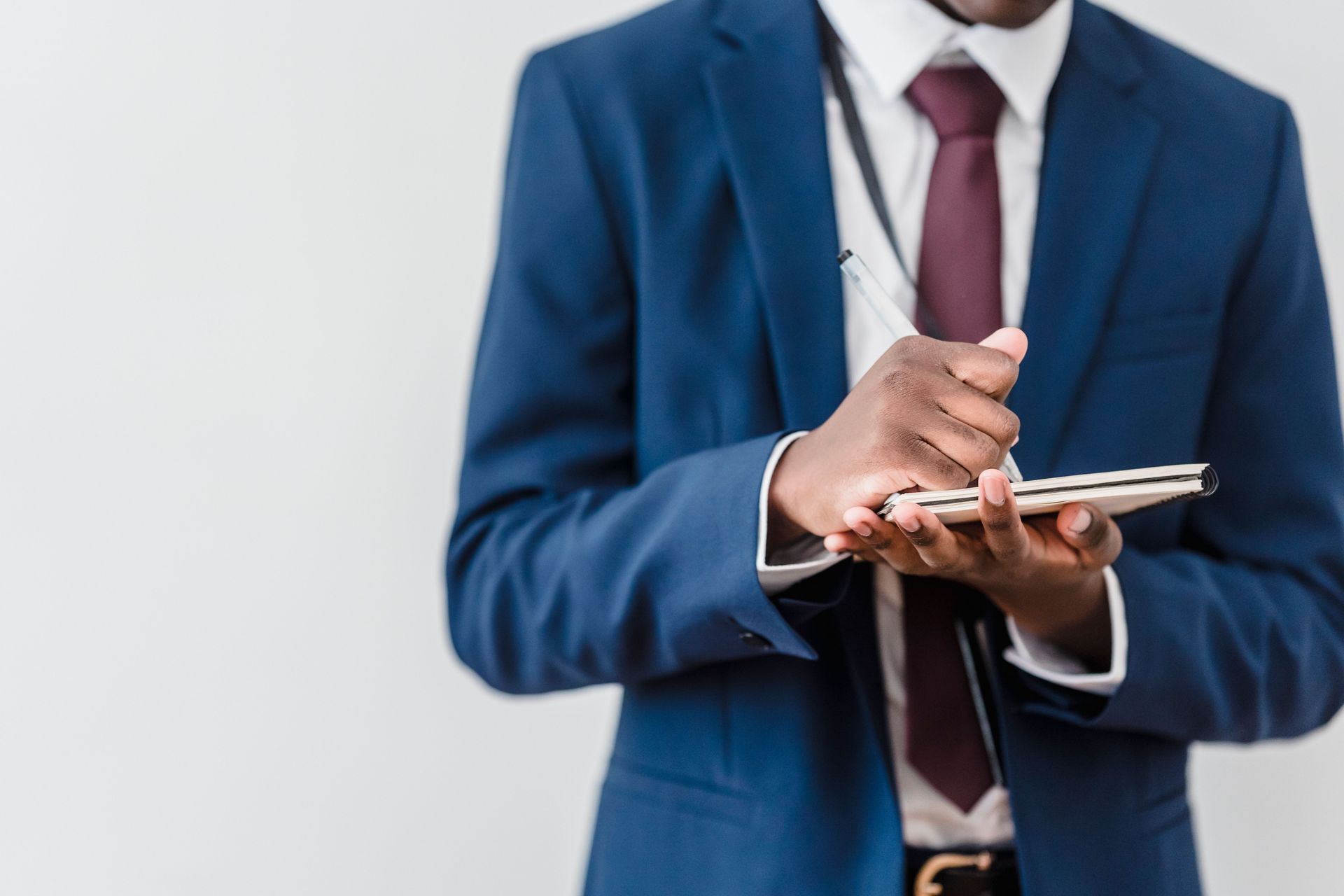 Businessperson in blue suit writing on a tablet against a white background