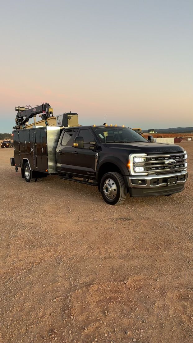 A black truck is parked in the middle of a dirt field.