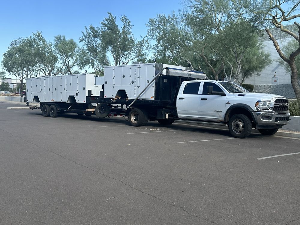 A white truck with a trailer attached to it is parked on the side of the road.