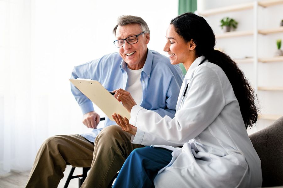 Doctor showing a clipboard to a seated patient in a bright clinic room Doctor showing a clipboard to a seated patient in a bright clinic room