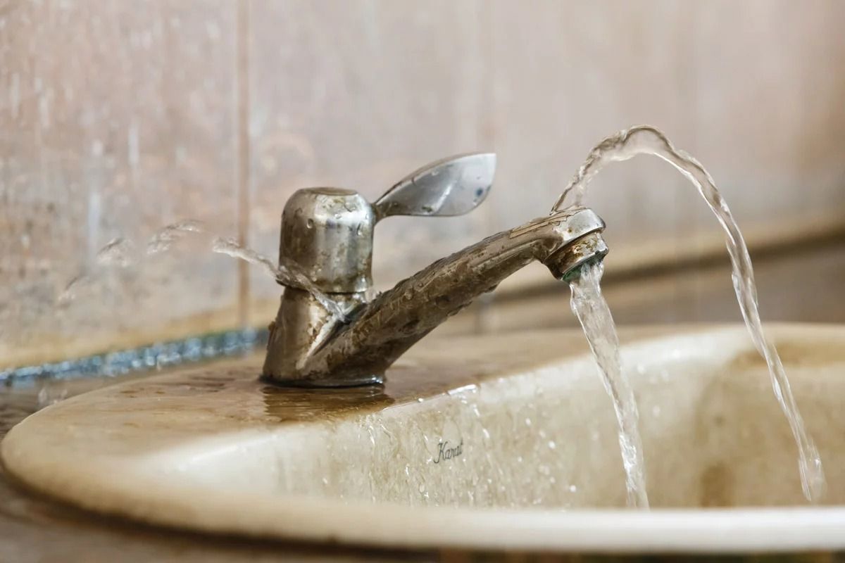 A faucet is leaking water into a sink.