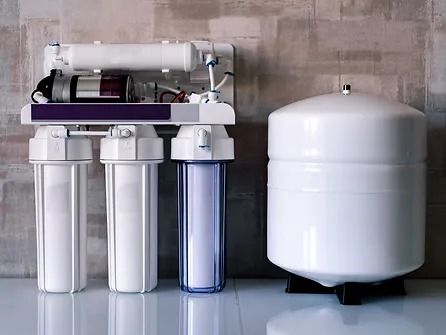 A water filter is sitting on a counter next to a tank.