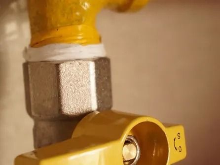 A close up of a yellow gas valve on a pipe.