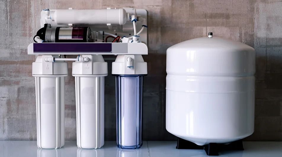 A water filter is sitting on a table next to a tank.