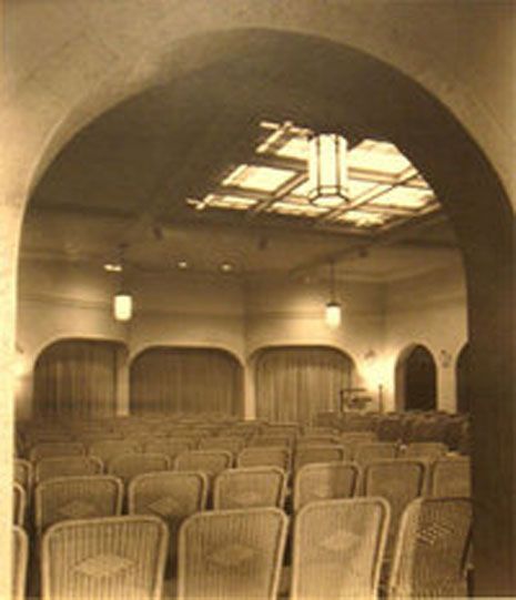 Empty vintage theater with rows of seats under warm lights and an arched ceiling