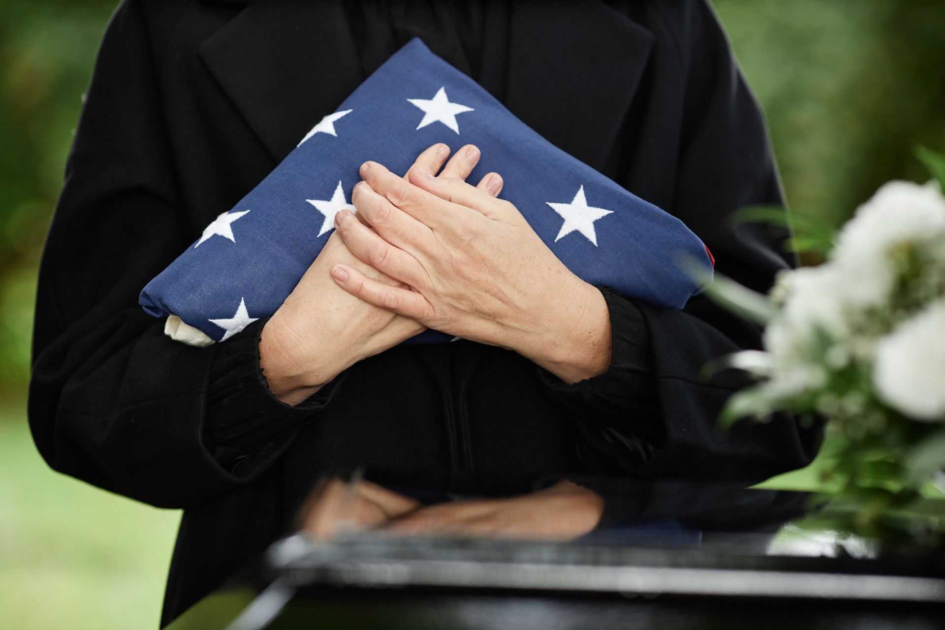 Folded U.S. flag held at a graveside, suggesting a military funeral