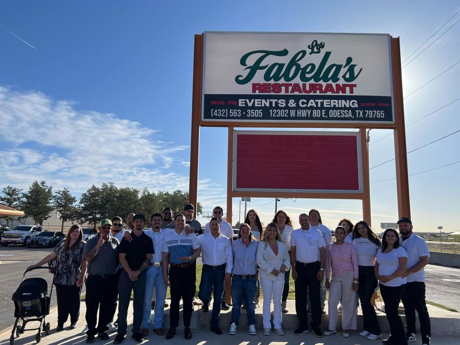 A group of people standing together in front of the Fabela's Restaurant sign outdoors on a sunny day.