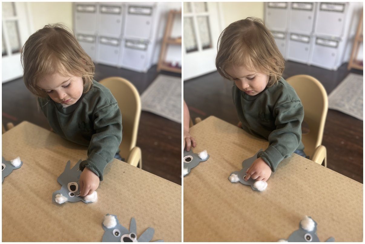 Child at a table, playing with small toy animals in a bright classroom.