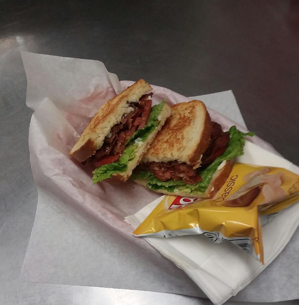 A toasted BLT sandwich with a side of chips in a basket.