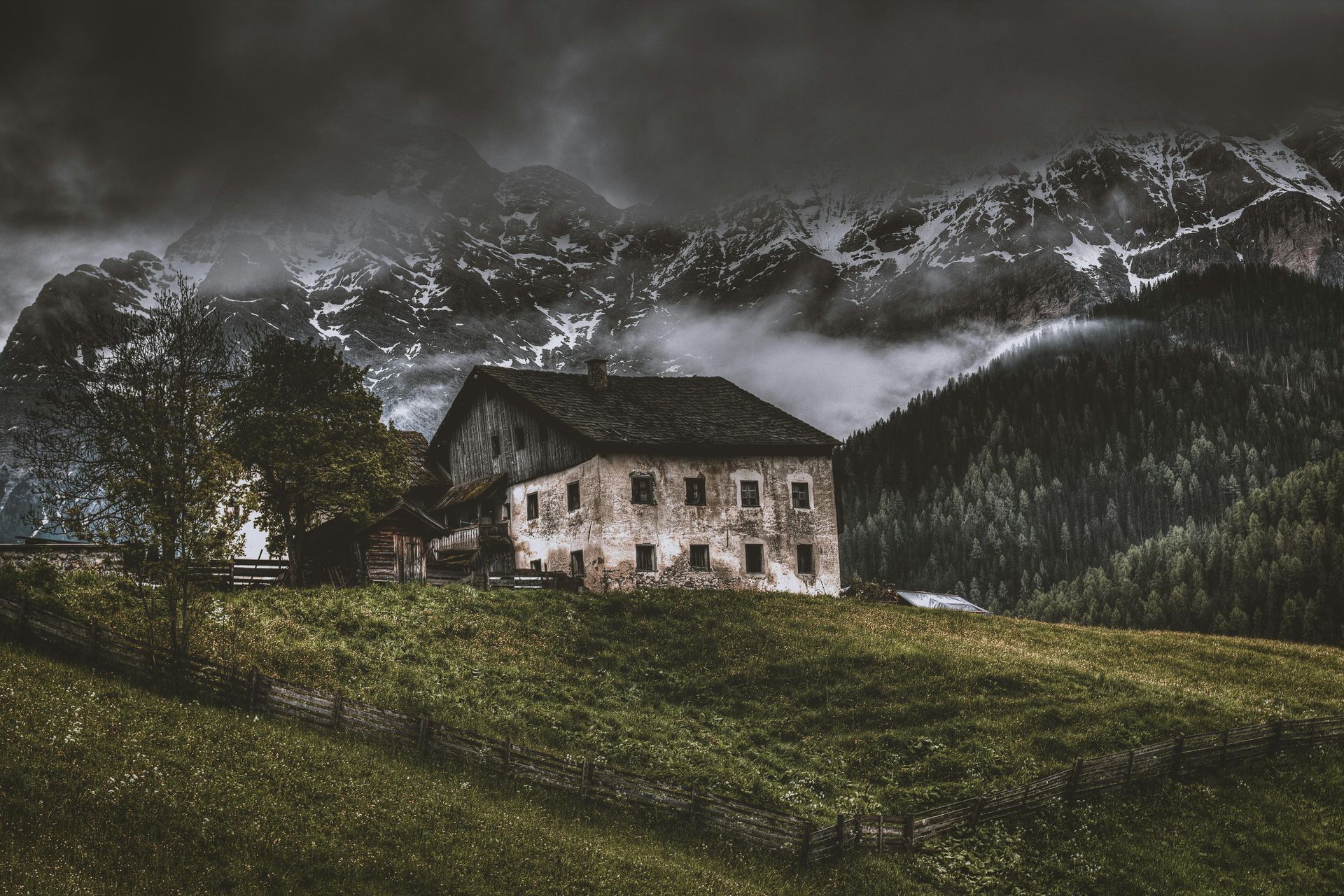 Il y a une maison au milieu d'un champ avec des montagnes en arrière-plan.