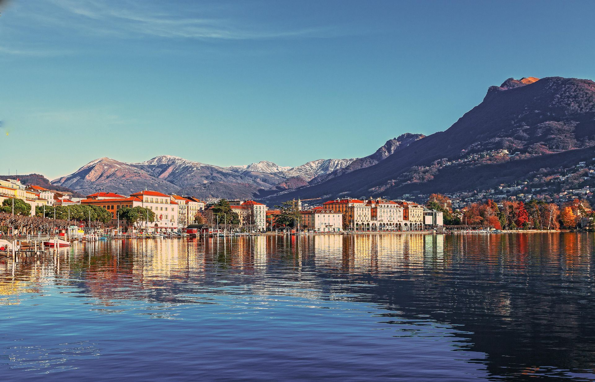 Une ville se reflète dans l'eau d'un lac avec des montagnes en arrière-plan.