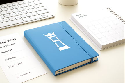 A blue notebook is sitting on a desk next to a keyboard.