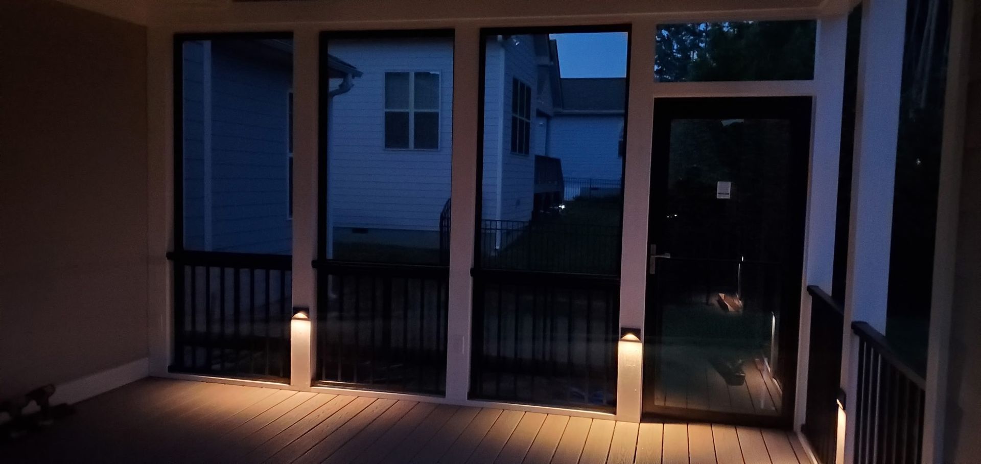 Dim porch walkway at dusk with two lit bollard lights and a house entrance in the background