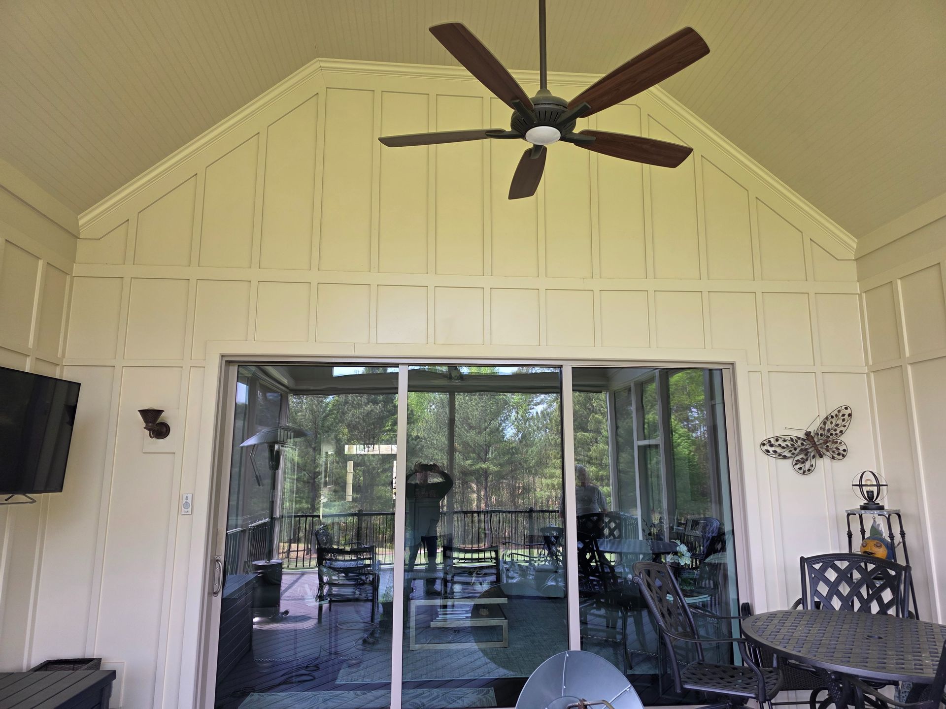 Covered patio with sliding glass doors, ceiling fan, and outdoor seating overlooking a screened pool area
