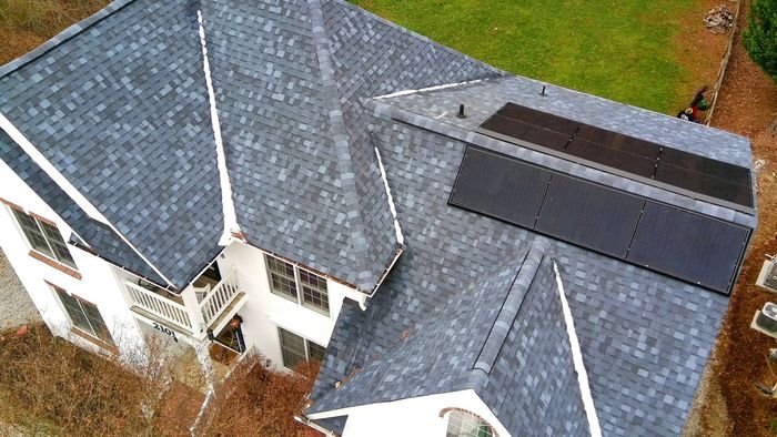 An aerial view of a house with solar panels on the roof.