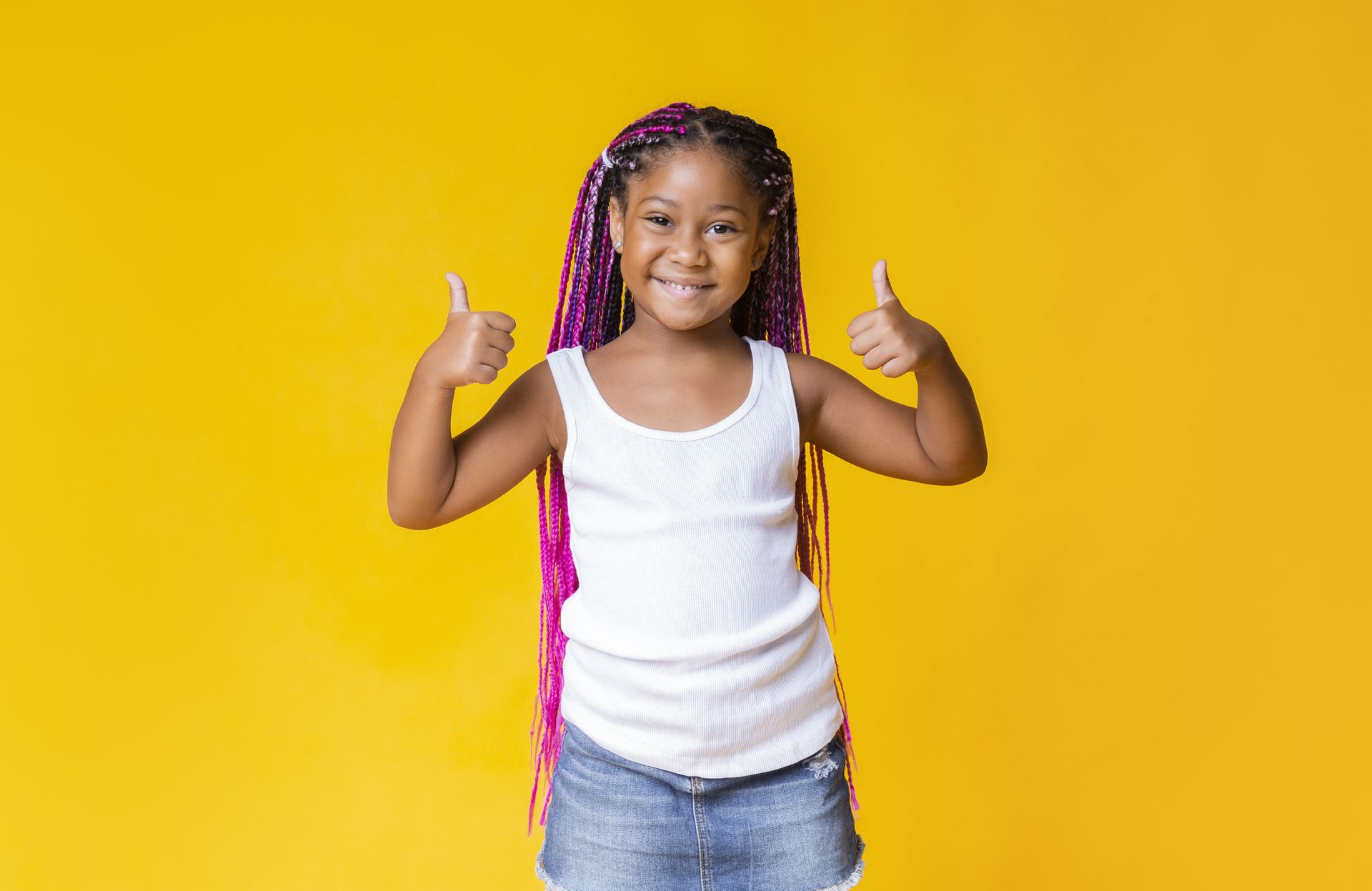 A little girl with purple braids is giving two thumbs up.