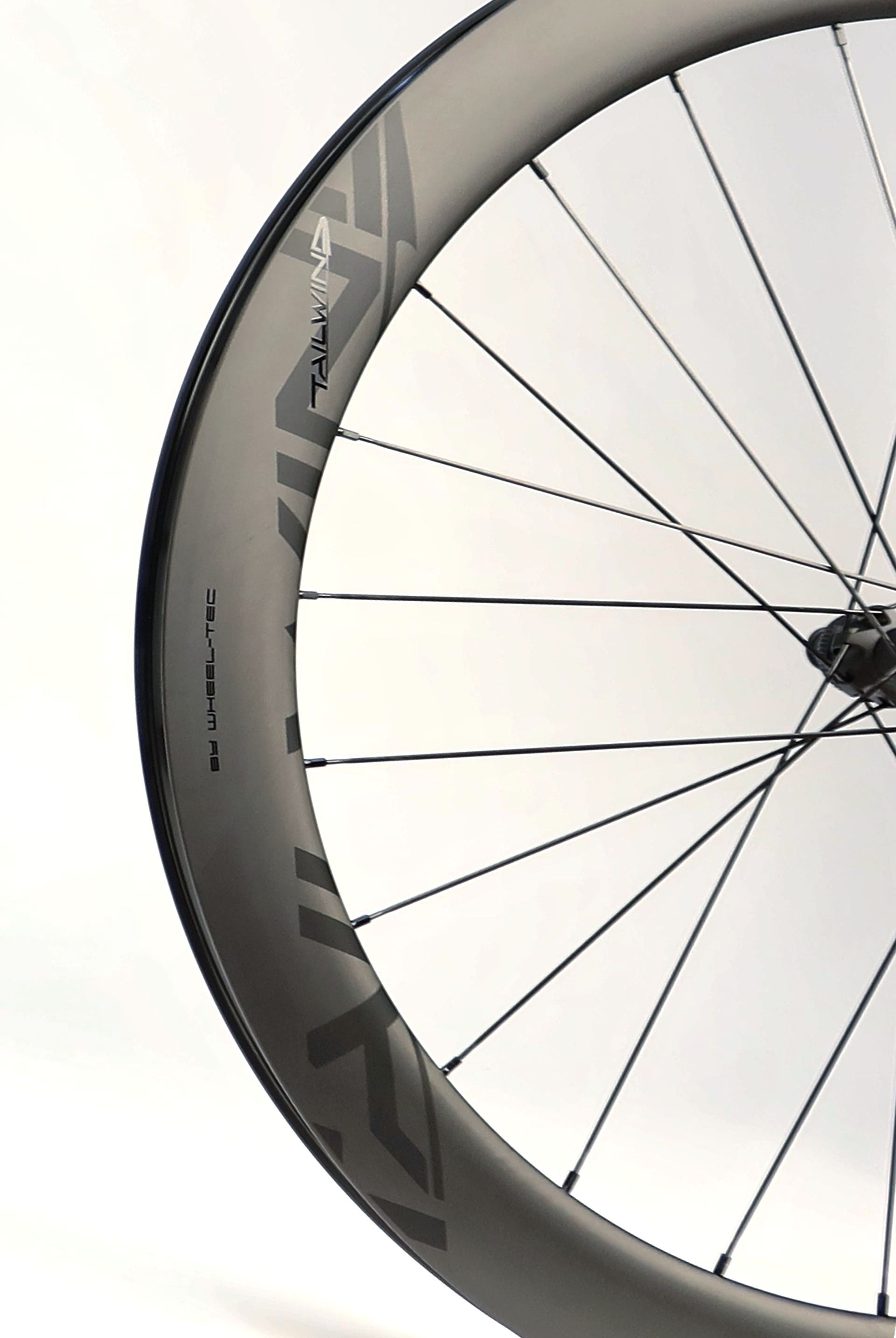 A close up of a carbon road bicycle wheel with subtle logo
