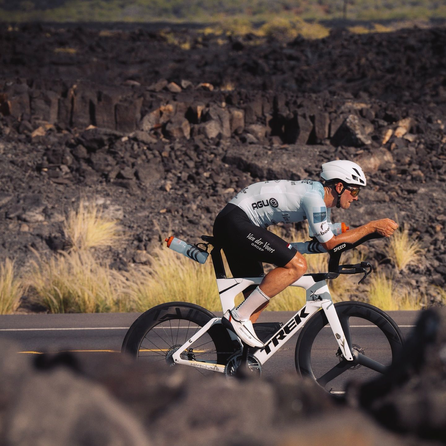 A man is riding a tt bike on a road with tailwind aero wheels.